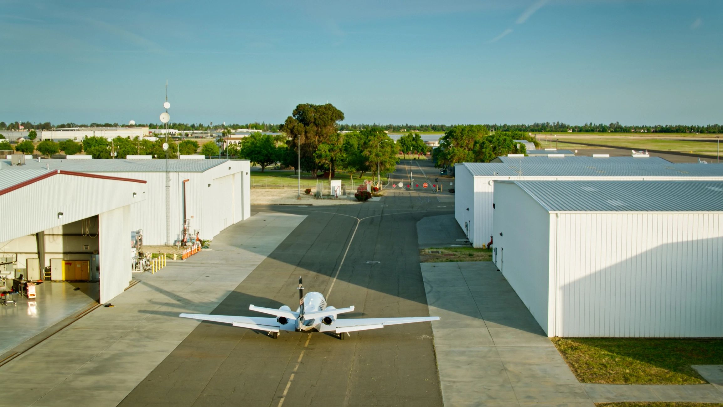 Private aircraft moving toward hangars at a small airfield